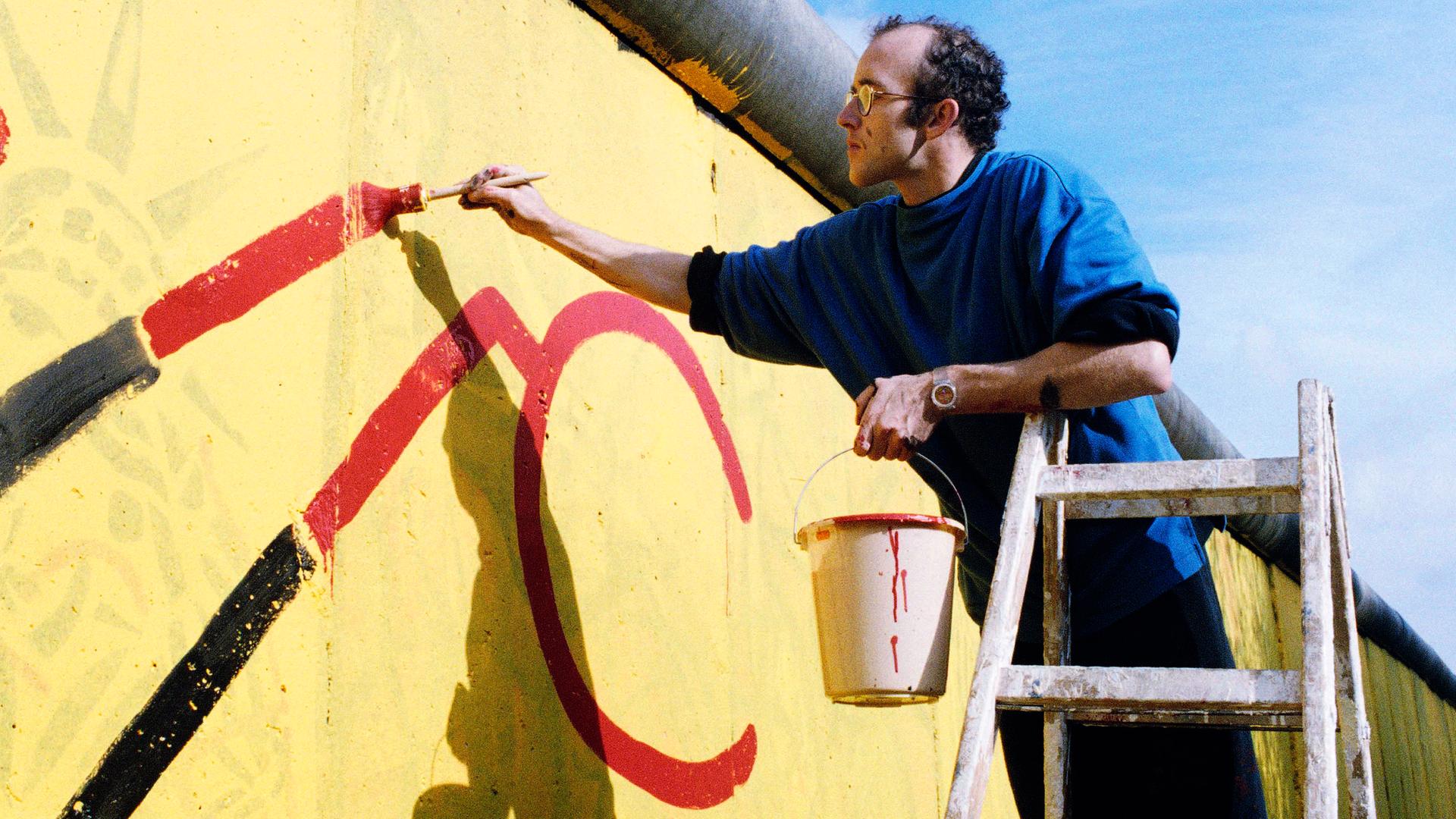 Der US-Künstler Keith Haring malt einen Teil der Berliner Mauer im Jahr 1986 an.