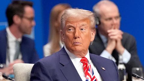 US-Präsident Donald Trump während einer Plenarsitzung der NATO in Brüssel. Er trägt einen dunkelblauen Anzug und eine Krawatte mit dem blau-weiß-roten Muster der Union-Jack-Flagge.