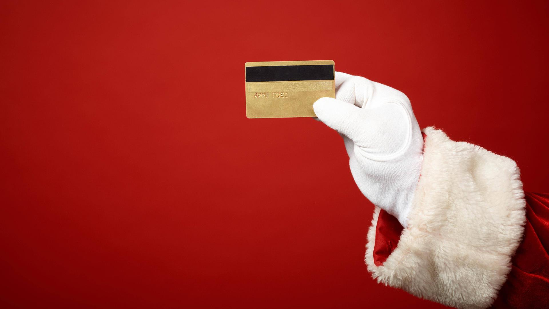 Illustration: Die Hand des Weihnachtsmanns hält eine goldene Kreditkarte.