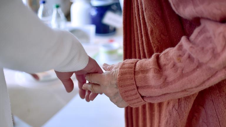  Eine Pflegekraft hält die Hand einer Bewohnerin einer Pflegeeinrichtung