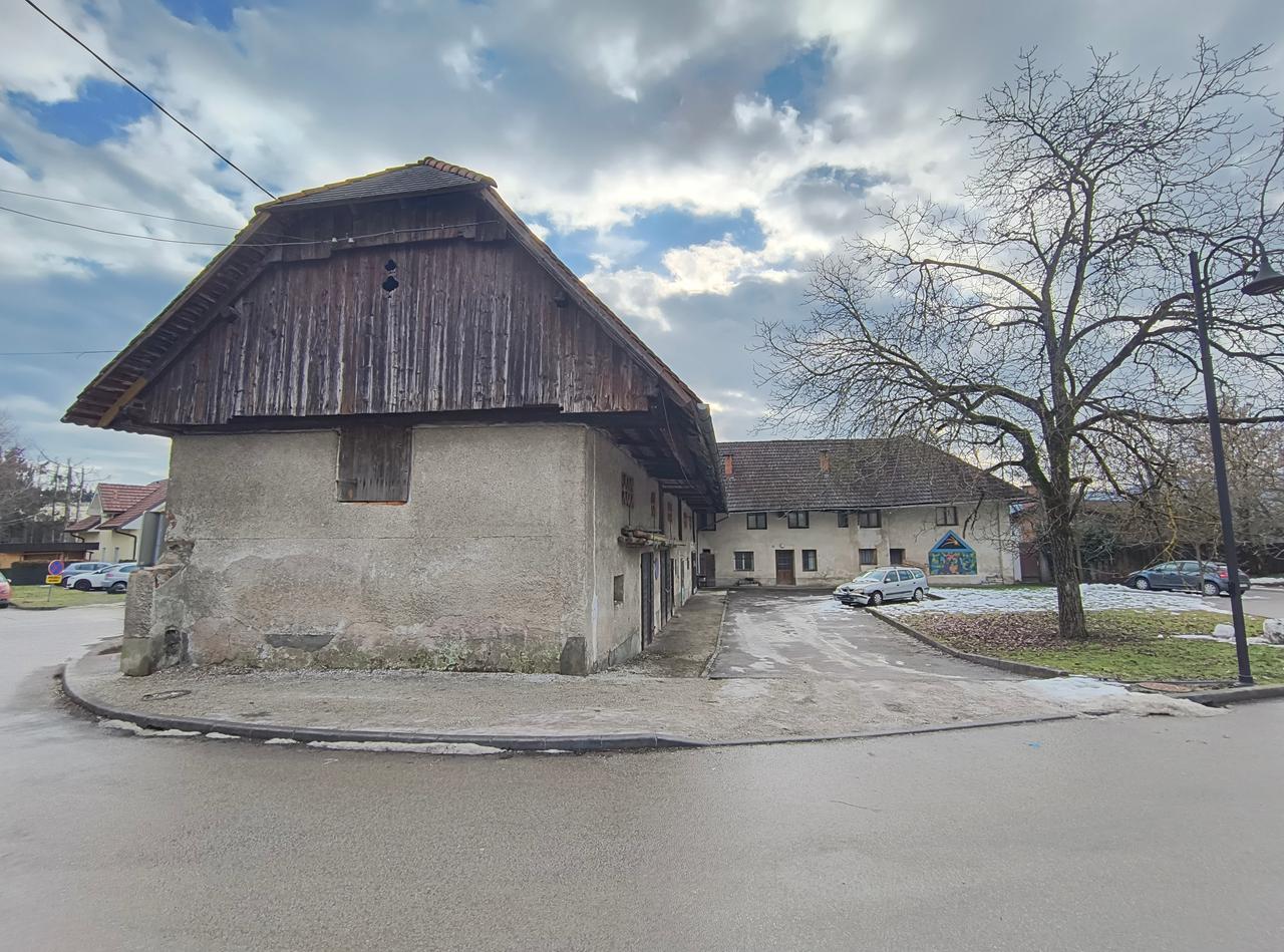 Ein altes, einstöckiges Gebäude, das einem Bauernhaus ähnelt, steht an einer Straßenecke im slowenischen Ort Mengeš