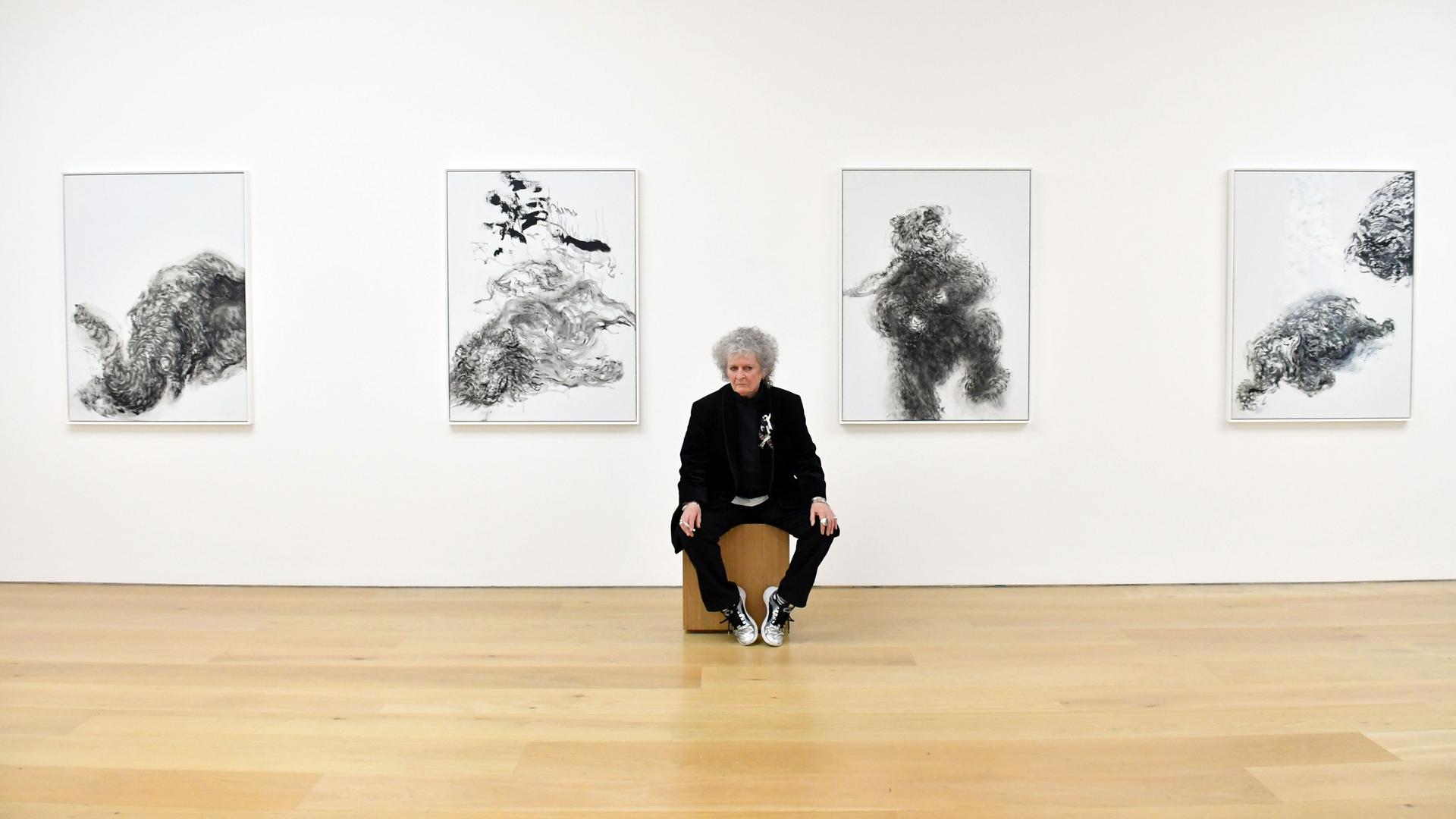 Die britische Künstlerin Maggi Hambling sitzt in der Londoner Marlborough Gallery auf einem Hocker vor vier Bildern. Die britische Künstlerin Maggi Hambling sitzt in der Londoner Marlborough Gallery auf einem Hocker vor vier Bildern.