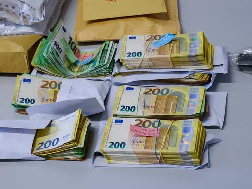Auf einem Tisch liegen mehrere Bündel mit Geldscheinen, die bei einer Razzia im Zusammenhang mit Geldwäsche gefunden wurden