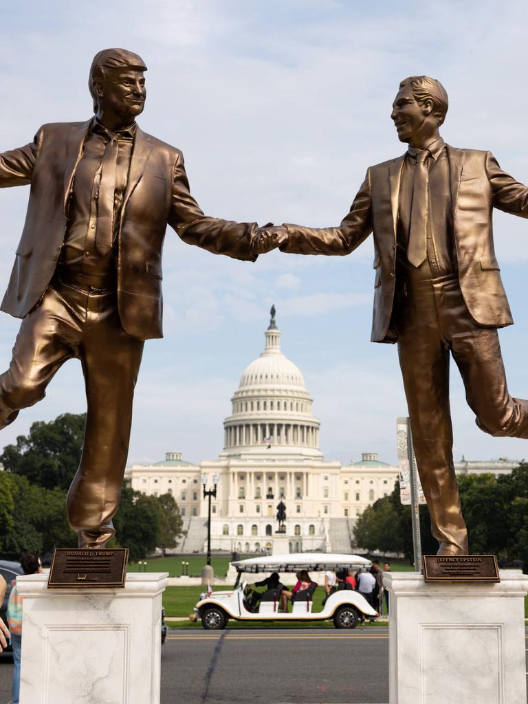 Eine Frau blickt auf Bronze farbene Statuen von US-Präsident Donald Trump und dem Sexualstraftäter Jeffrey Epstein, die sich an den Händen halten und vor dem Kapitol in Washington tanzen. 