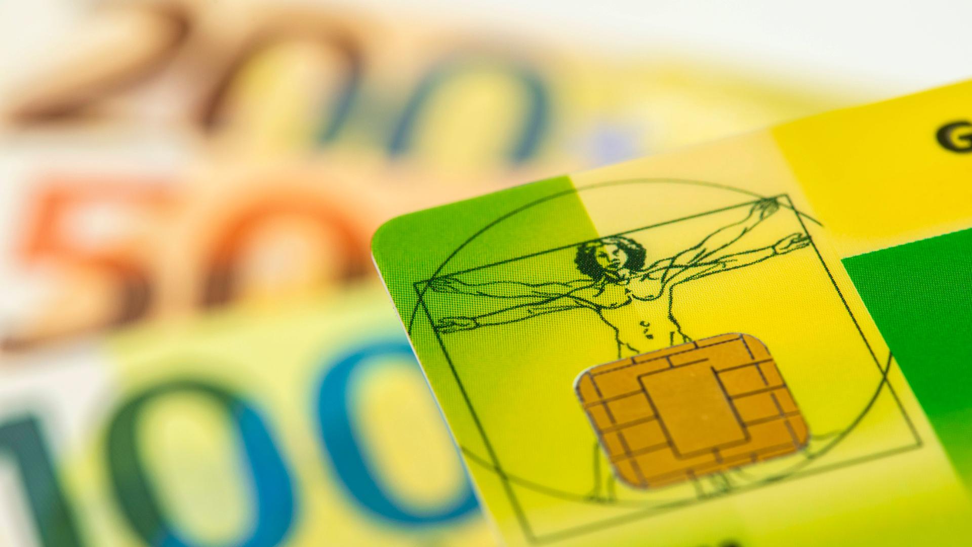 Eine Gesundheitskarte liegt auf vielen Euro Banknoten als Symbolbild für steigende Krankenkassenbeiträge und notwendige Reformen im Gesundheitssystem
