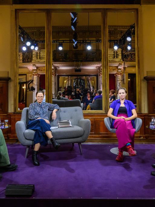 Adam Soboczynski, Thea Dorn, Cara Platte und Juli Zeh sitzen auf der Bühne, an den Seiten sitzen Zuschauer.
