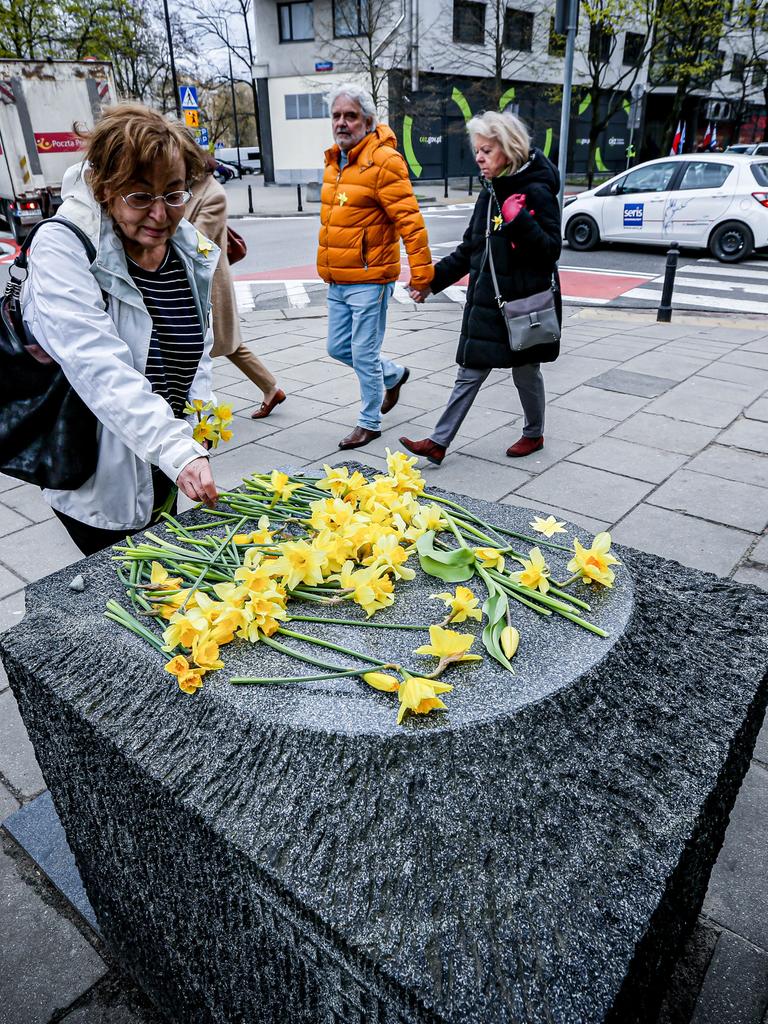 Eine Frau legt gelbe Blumen am Denkmal für die Ghetto-Helden im Warschauer Stadtteil Muranow ab