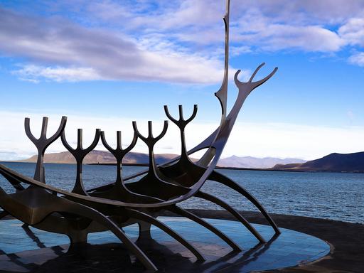 Blick zu früher Abendstunde auf die Edelstahlskulptur, die Richtung Meer weist.