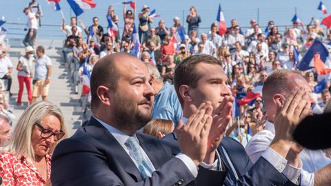 David Rachline applaudiert bei einer Veranstaltung. Im Hintergrund schwenken Menschen französische Flaggen.