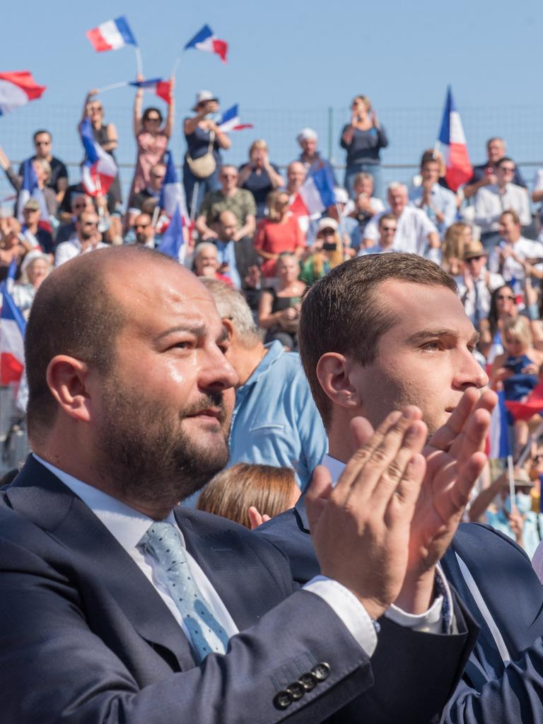 David Rachline applaudiert bei einer Veranstaltung. Im Hintergrund schwenken Menschen französische Flaggen.