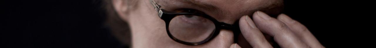 Martin Bühler schaut durch seine Brille während er nach seiner Brille greift.