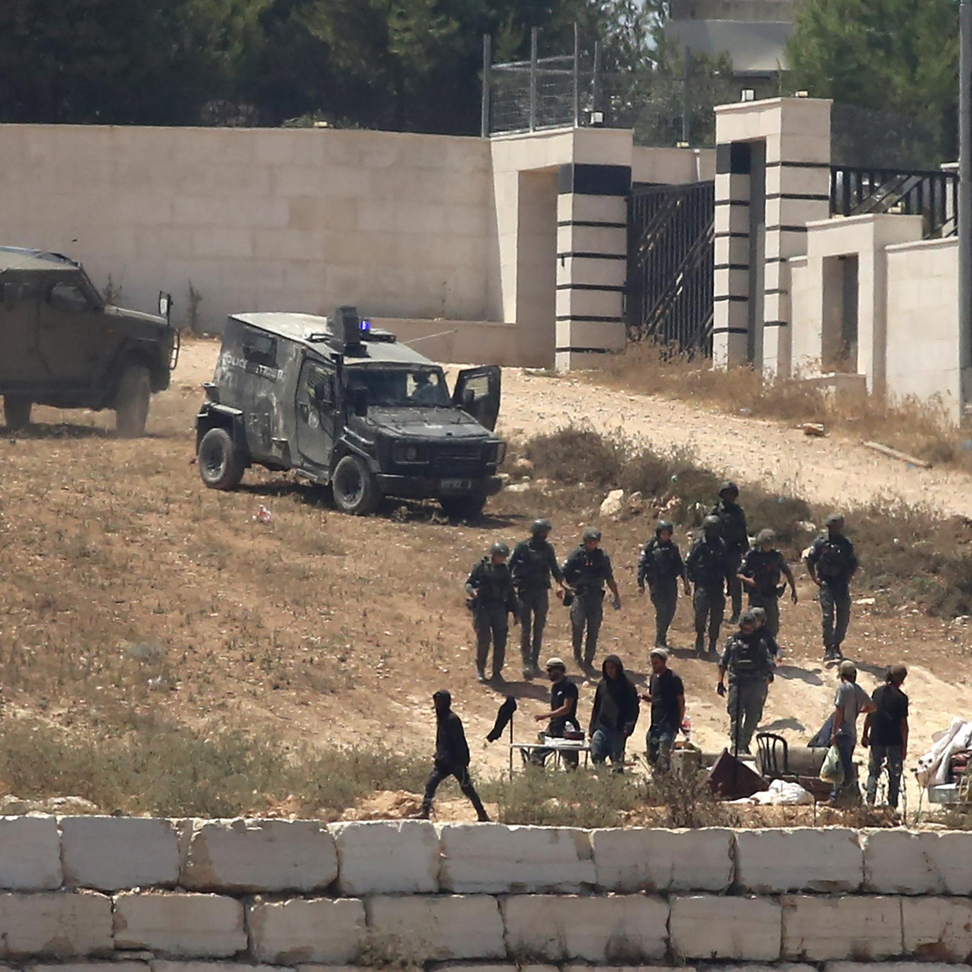 Israelische Soldaten stehen im besetzten Westjordanland im Dorf Kusra südlich von Nablus neben Siedlern Wache vor palästinensischen Häusern, die sie abgeriegelt haben.