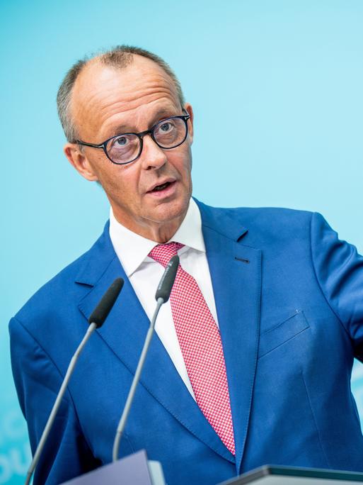 Friedrich Merz steht an einem Rednerpult und macht eine weit ausholende Geste mit seiner linken Hand, in der er einen Kugelschreiber hält.