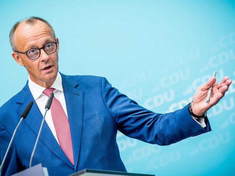 Friedrich Merz steht an einem Rednerpult und macht eine weit ausholende Geste mit seiner linken Hand, in der er einen Kugelschreiber hält.