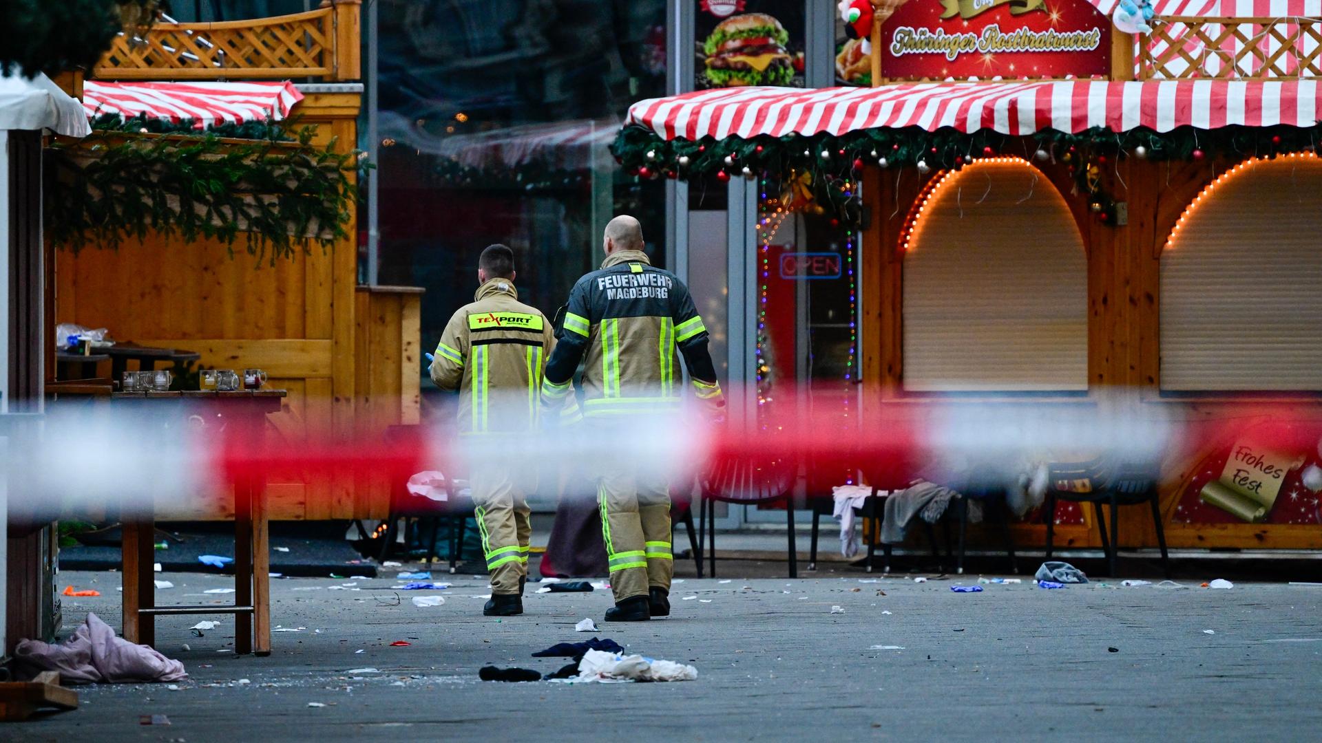 Das Bild zeigt zwei Rettungskräfte, die den Tatort am Magdeburger Weihnachtsmarkt begehen.