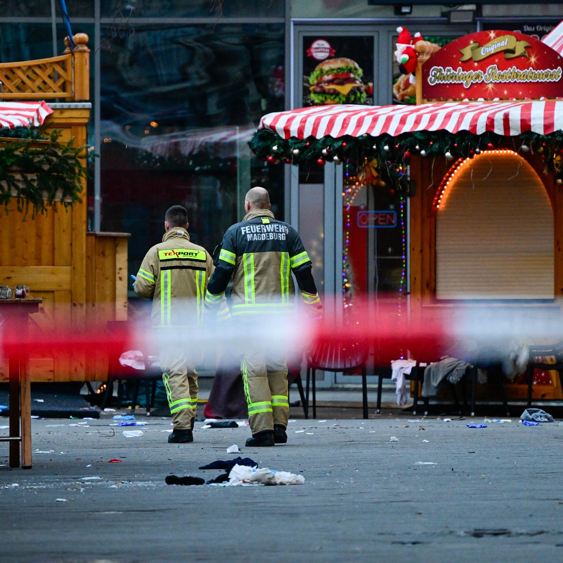 Das Bild zeigt zwei Rettungskräfte, die den Tatort am Magdeburger Weihnachtsmarkt begehen.