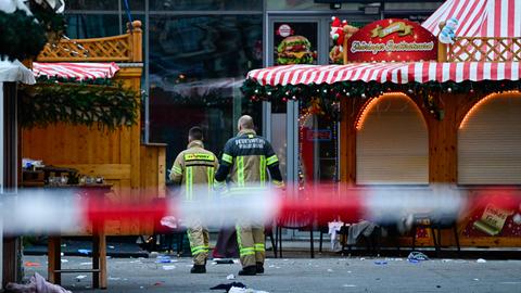 Das Bild zeigt zwei Rettungskräfte, die den Tatort am Magdeburger Weihnachtsmarkt begehen.