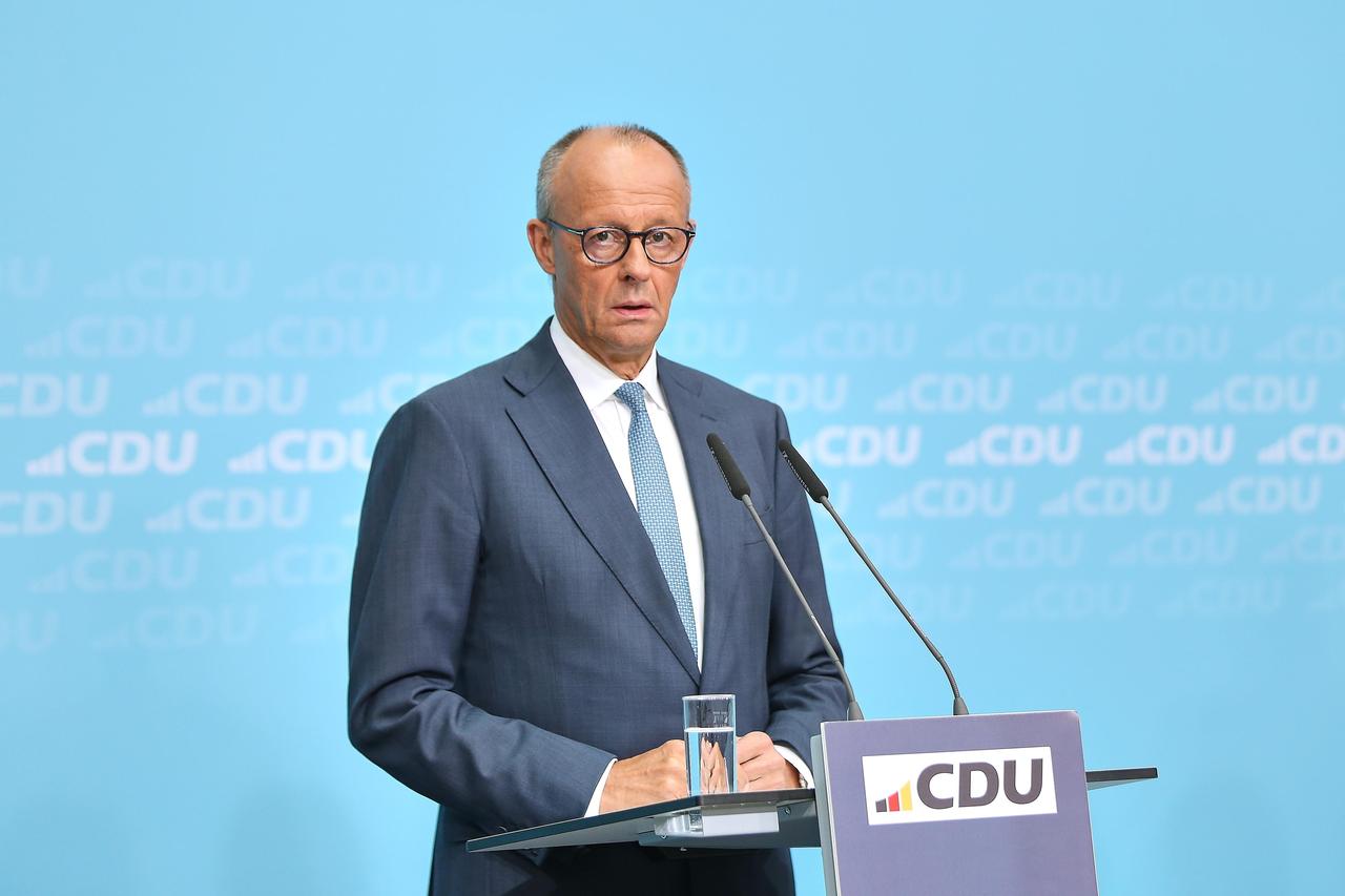 Bundes-Kanzler Friedrich Merz steht an einem Redner-Pult mit der Aufschrift CDU. Er schaut betroffen.