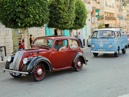 Ein Oldtimer und ein alter VW-Bulli fahren durch die Straßen von Jerusalem. Ein Oldtimer und ein alter VW-Bulli fahren durch die Straßen von Jerusalem.