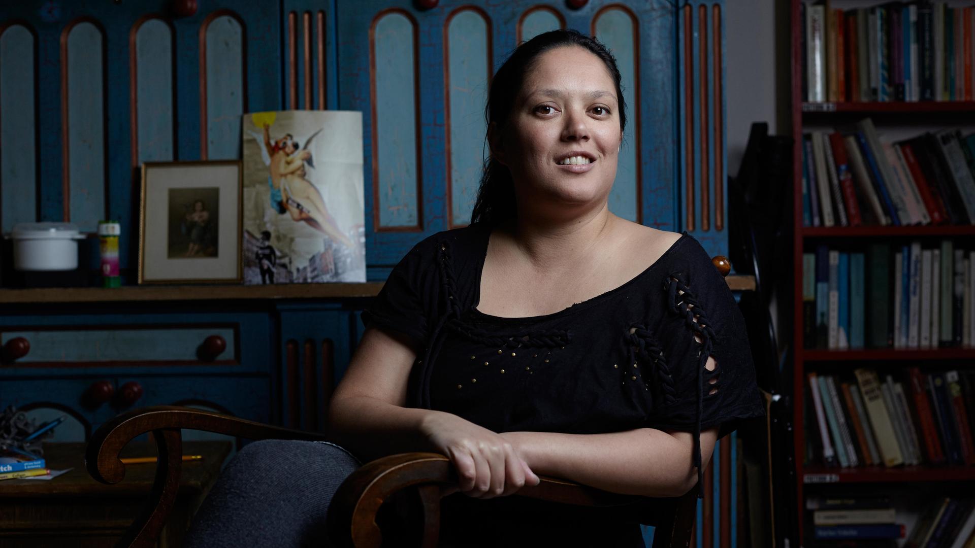 Poträtfoto der Autorin Jacinta Nandi in Berlin. Im Hintergrund sind Bücher in einem Regal aufgereiht. Poträtfoto der Autorin Jacinta Nandi in Berlin. Im Hintergrund sind Bücher in einem Regal aufgereiht.