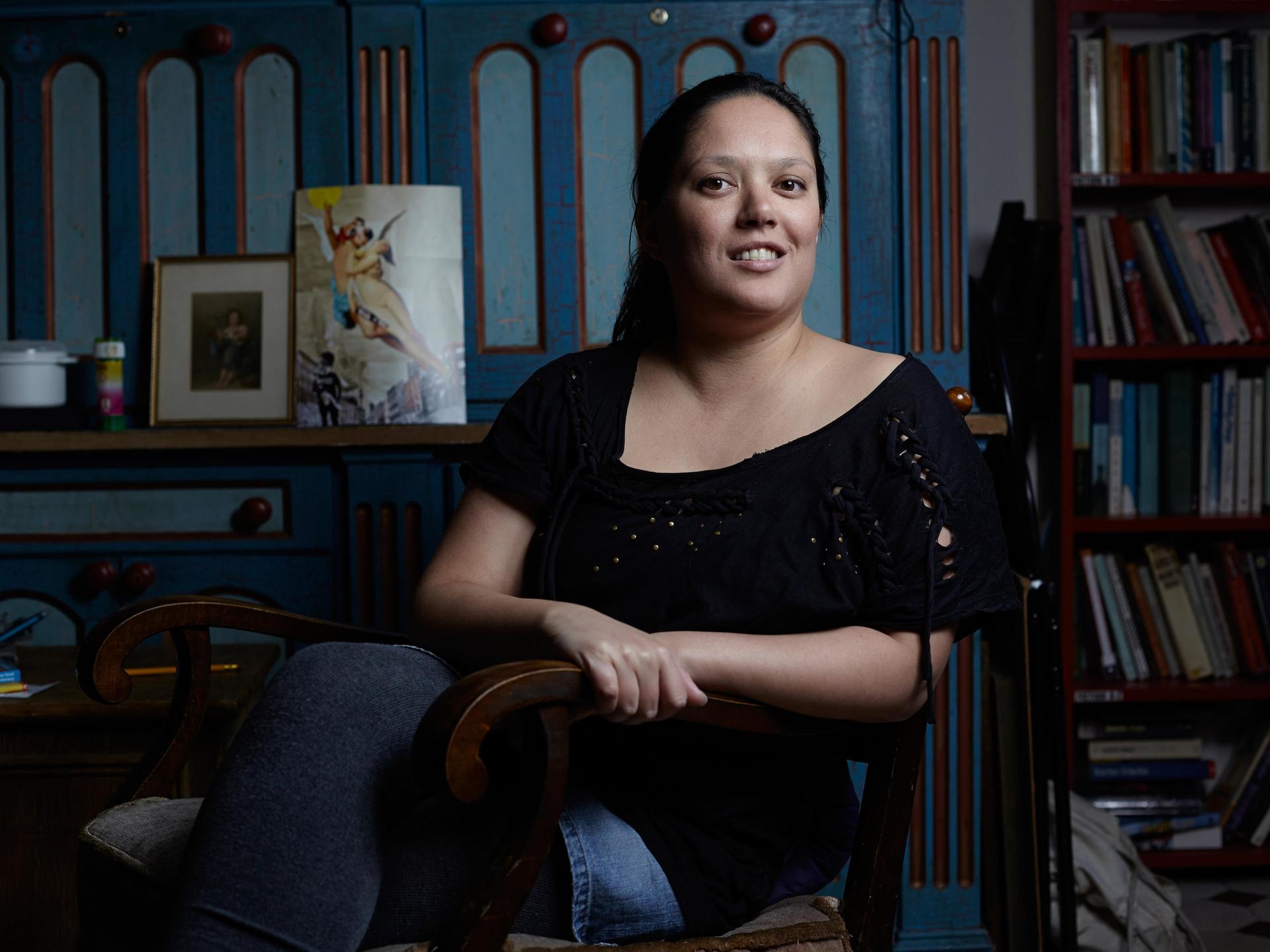 Poträtfoto der Autorin Jacinta Nandi in Berlin. Im Hintergrund sind Bücher in einem Regal aufgereiht.
