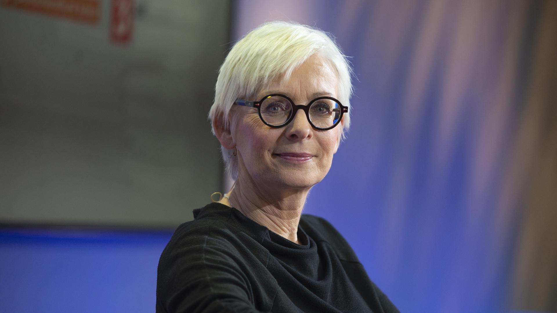 Die Schriftstellerin Dörte Hansen im Porträt mit hellblonden, kurzen Haaren und dunkler Brille vor blauem Hintergrund Die Schriftstellerin Dörte Hansen im Porträt mit hellblonden, kurzen Haaren und dunkler Brille vor blauem Hintergrund