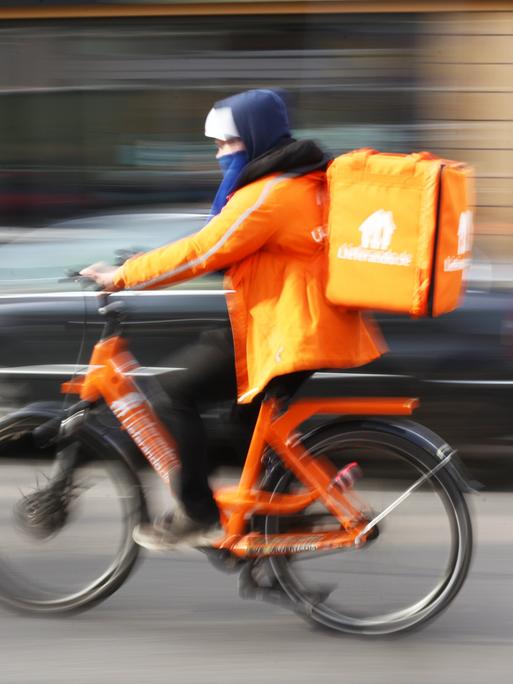 Ein Fahrer von Lieferando fährt auf seinem Rad in Berlin im Bezirk Mitte auf der Friedrichstraße