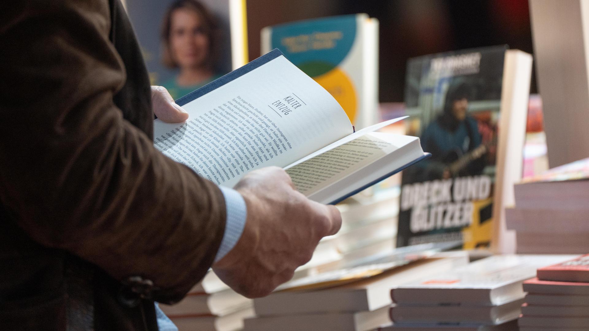 Ein Mann hält ein aufgeschlagenes Buch in den Händen. 