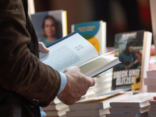 Ein Mann hält ein aufgeschlagenes Buch in den Händen. 