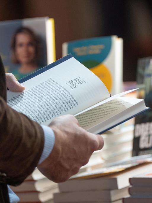 Ein Mann hält ein aufgeschlagenes Buch in den Händen. 