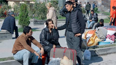 Geflüchtete aus Bergkarabach Ende September 2023 ruhen sich nach ihrer Ankuft in der armenischen Stadt Goris auf Stufen aus.