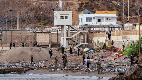 Soldaten der spanischen Armee und Beamte der Guardia Civil stehen Wache, während Migranten aus der spanischen Exklave Ceuta nach Marokko zurückkehren.
