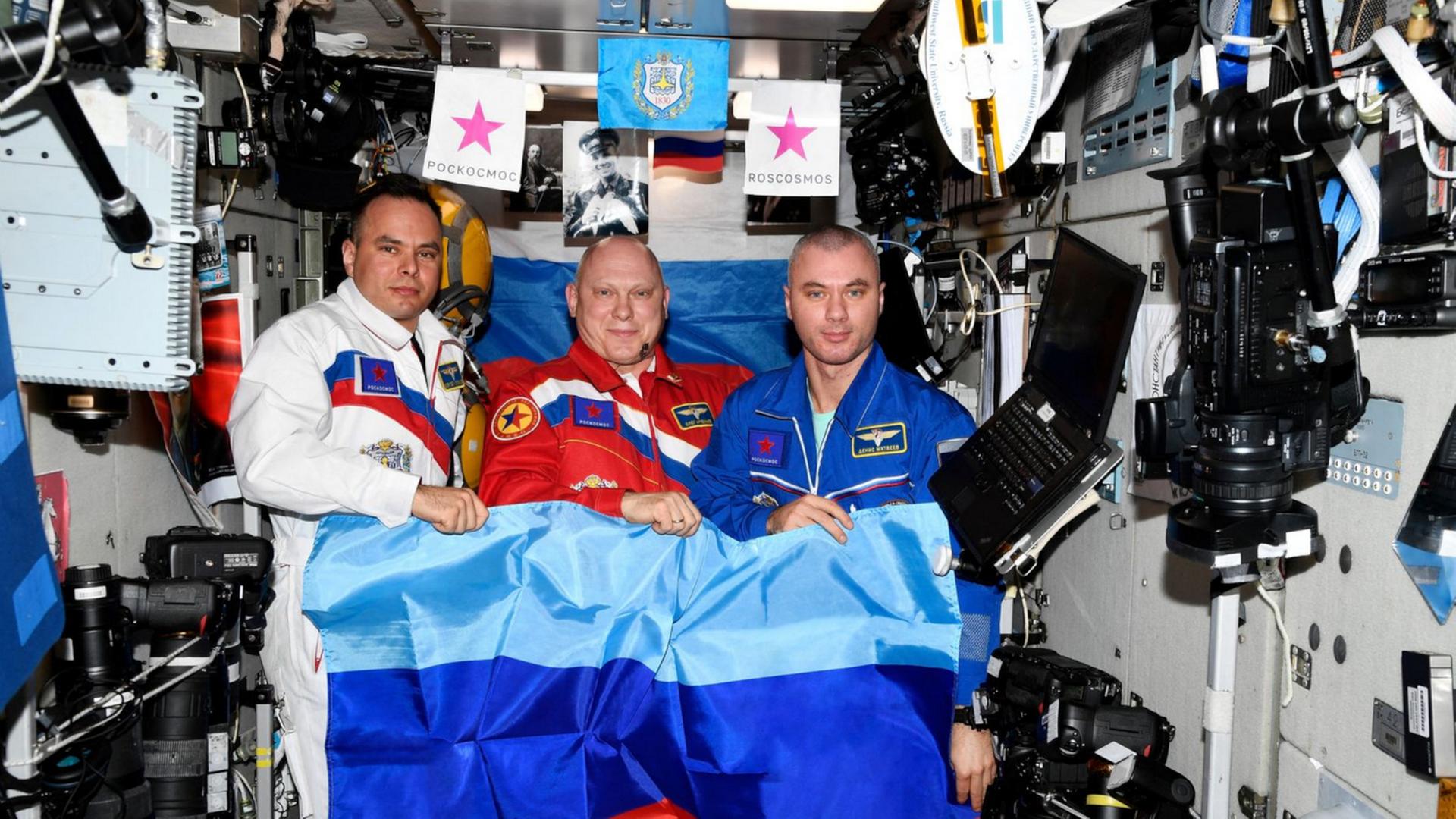 Das Ende aller ISS-Illusionen: Drei Kosmonauten – gekleidet in die russischen Nationalfarben – posieren auf der Raumstation mit der Flagge der besetzten „Volksrepublik“ Luhansk.