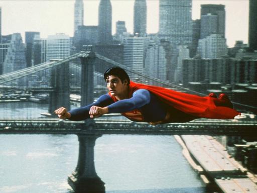 Christopher Reeve im blau-roten Supermankostüm fliegt über New York City in einem Superman-Film von 1980 