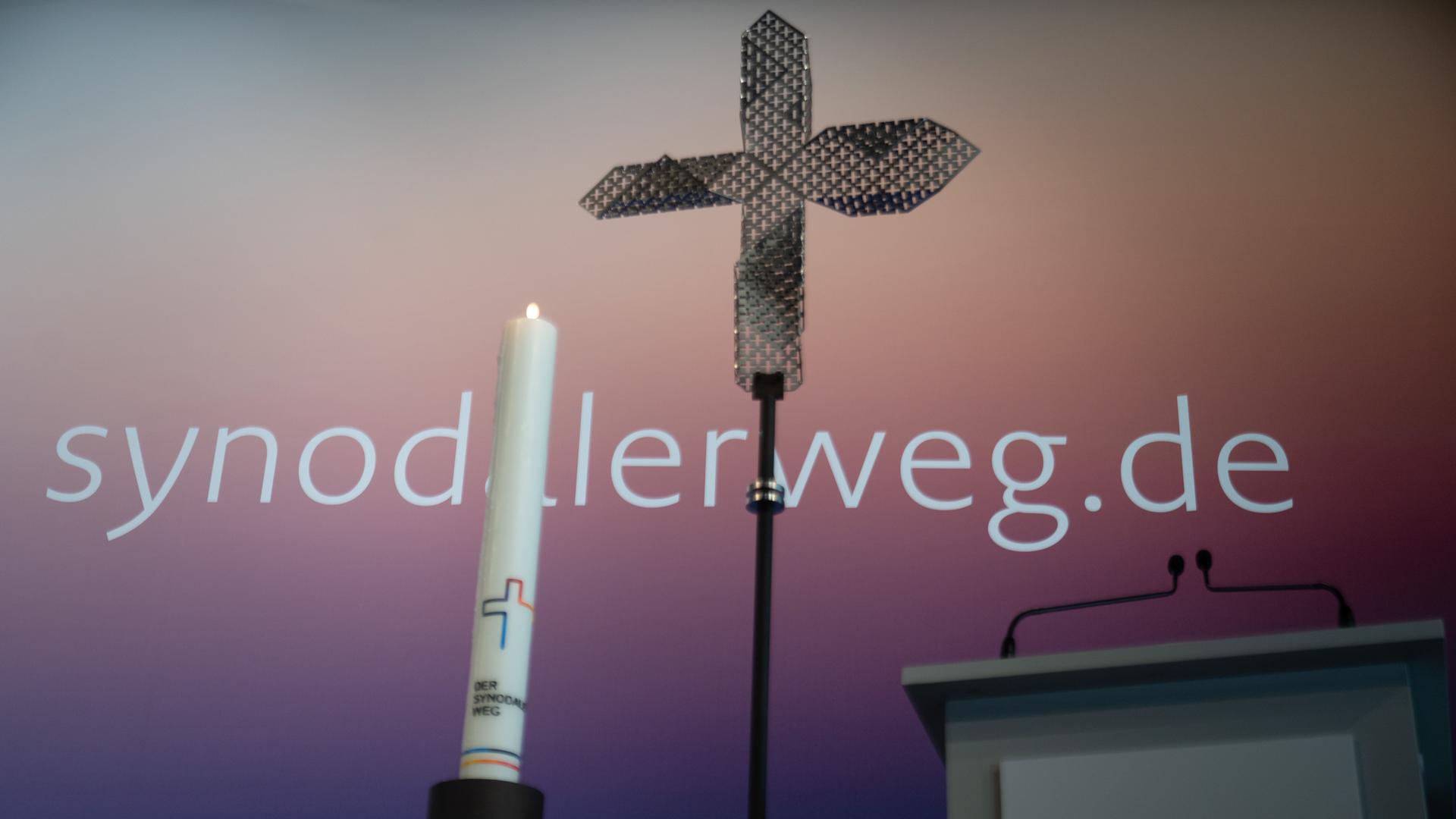 Eine Kerze und ein Kreuz stehen zu Beginn der Dritten Synodalversammlung der deutschen Katholiken vor dem Schriftzug "synodalerweg.de".