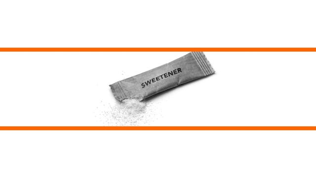 Schwarz-weißes Bild von einem Sachez Süßstoff vor weißem Hintergrund im mittleren Drittel des Bildes. Die beiden weißen Bilddrittel oben und unten sind mit orangenen Streifen abgetrennt.