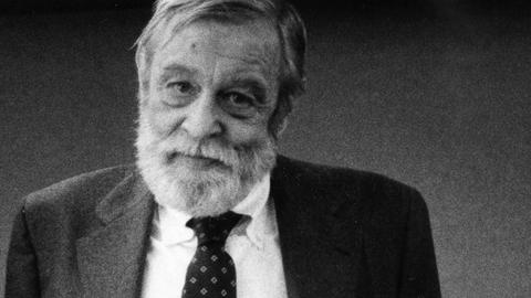 Schwarz-Weiß-Fotografie von Richard Yates, der einen grauen Anzug trägt und freundlich in die Kamera schaut.