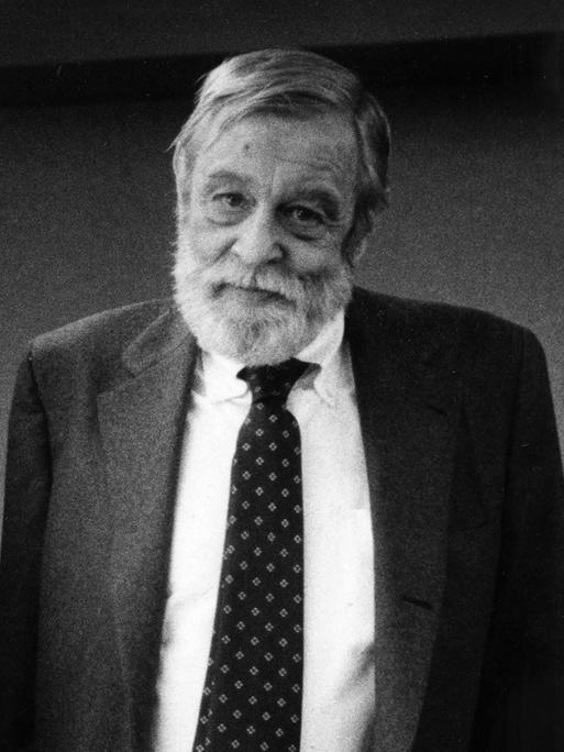 Schwarz-Weiß-Fotografie von Richard Yates, der einen grauen Anzug trägt und freundlich in die Kamera schaut.