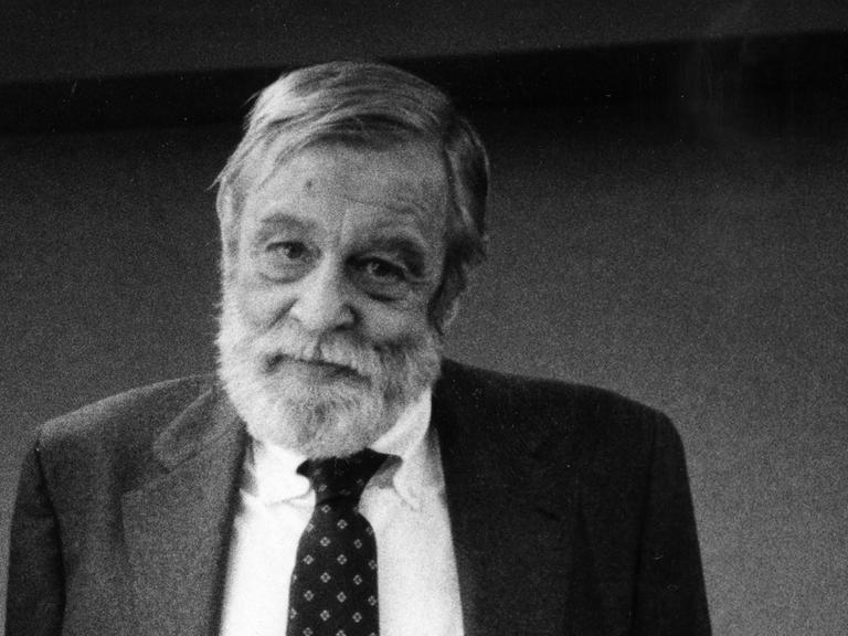 Schwarz-Weiß-Fotografie von Richard Yates, der einen grauen Anzug trägt und freundlich in die Kamera schaut.