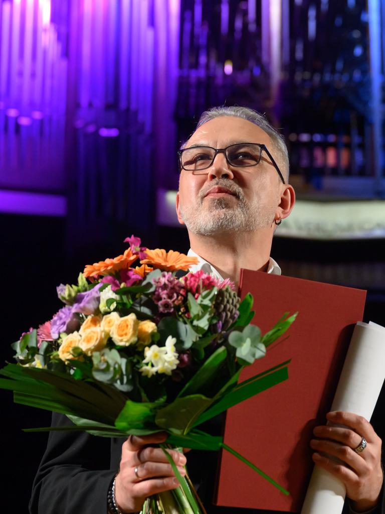 Bei der Auszeichnung mit dem Buchpreis zur Europäischen Verständigung steht der belarussische Schriftsteller Alhierd Bacharevič mit einem Blumenstrauß auf einer Bühne.