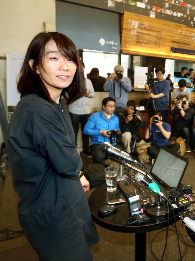 Literaturnobelpreisträgerin Han Kang steht bei einer Pressekonferenz vor einem Tisch mit Mikrofonen und Laptops, dahinter sind Medienvertretende.