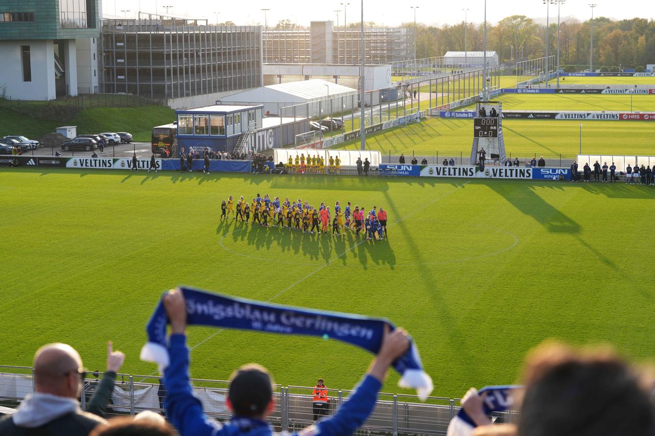 Auf der Tribüne halten Schalker Fans ihre Schals nach oben.