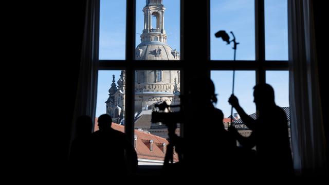 Journalisten zeichnen sich im Residenzschloss während einer Pressekonferenz vor der Frauenkirche als Silhouetten ab.