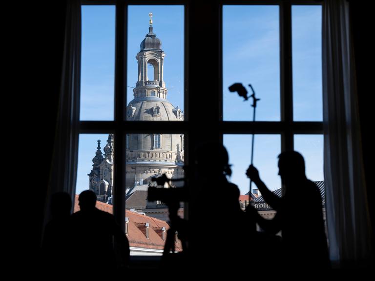 Journalisten zeichnen sich im Residenzschloss während einer Pressekonferenz vor der Frauenkirche als Silhouetten ab. Journalisten zeichnen sich im Residenzschloss während einer Pressekonferenz vor der Frauenkirche als Silhouetten ab.