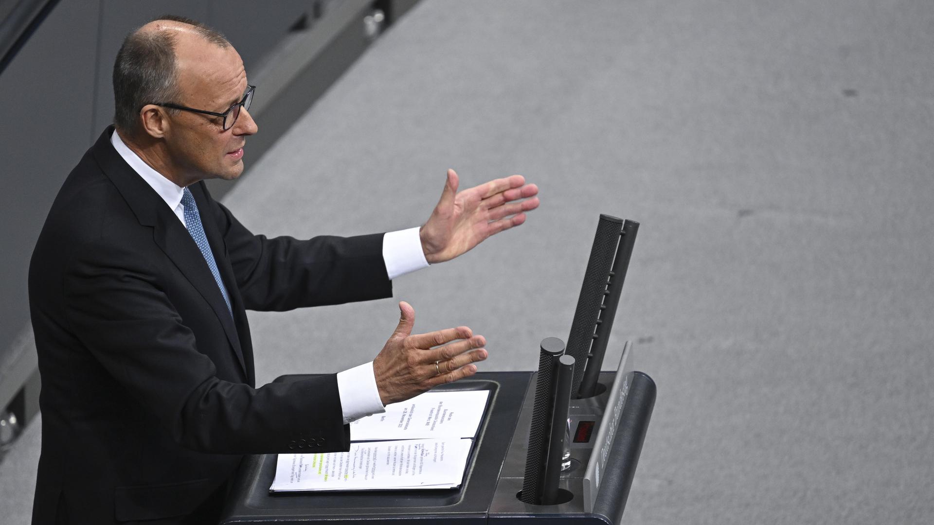 Bundeskanzler Friedrich Merz (CDU) steht mit offenen Händen am Rednerpult im Deutschen Bundestag