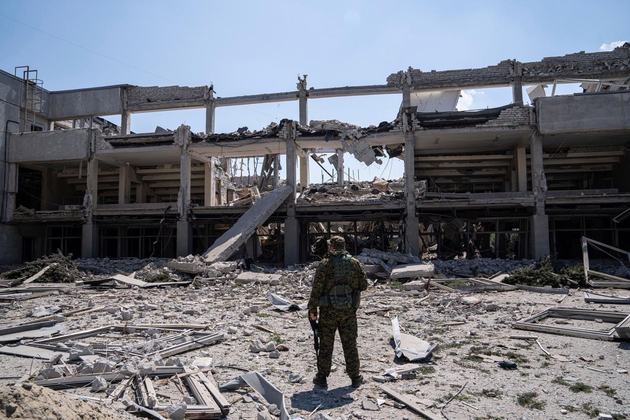 Ukraine, Charkiw: Ein ukrainischer Soldat blickt auf die durch einen russischen Angriff zerstörte Nationale Pädagogische Universität.