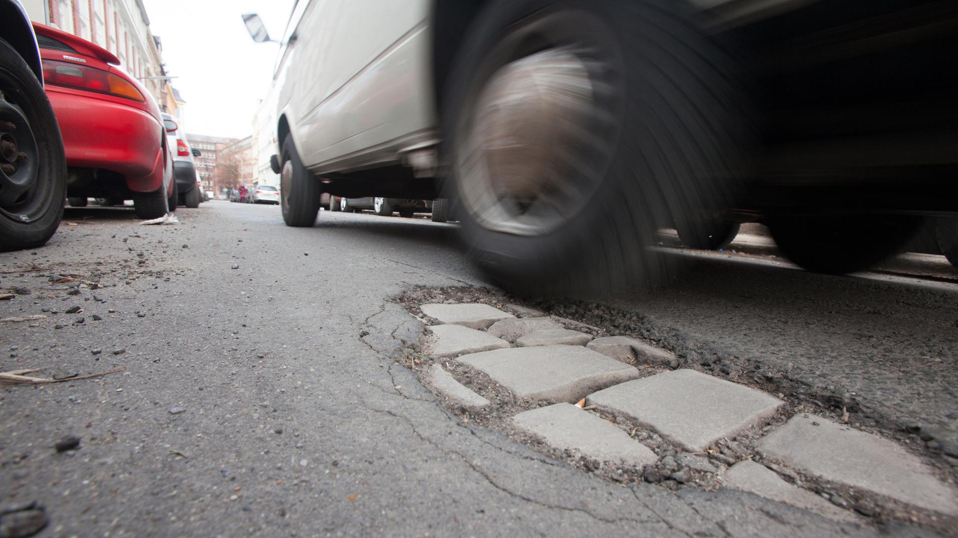 Ausgebrochener Asphalt auf einer von Autos befahrenen Straße