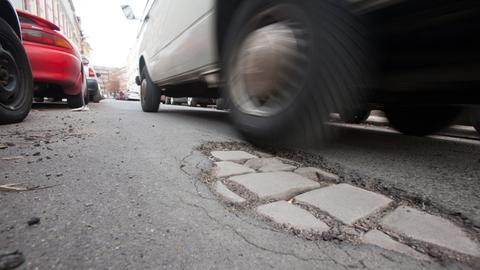Ausgebrochener Asphalt auf einer von Autos befahrenen Straße