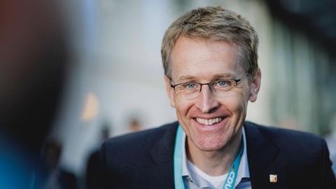 Daniel Günther, CDU, Ministerpraesident von Schleswig-Holstein. Er trägt ein blaues Hemd, ein dunkles Jacket und schaut in die Kamera.