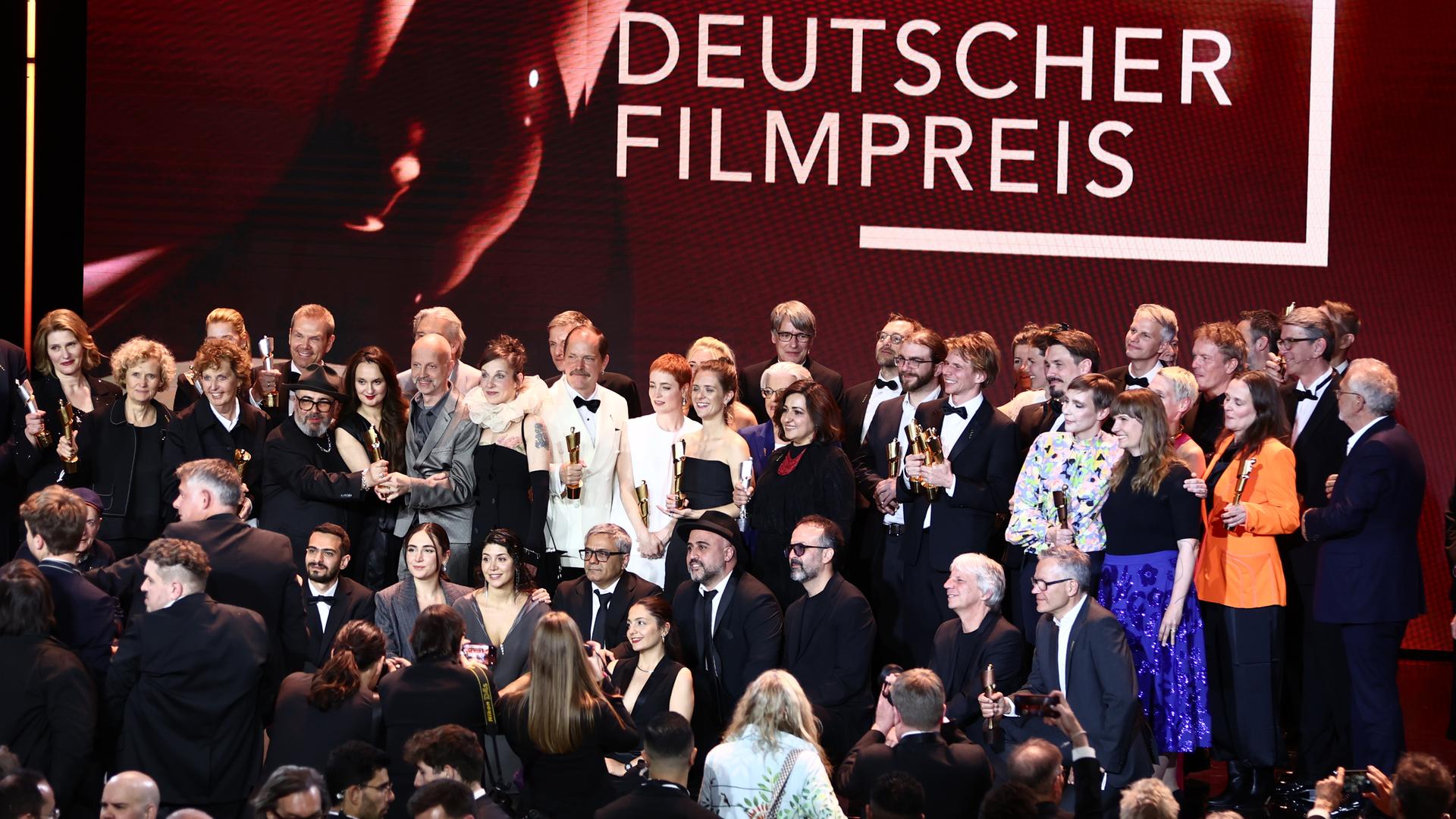 Die Personen stehen dicht beieinander zum Gruppenfoto in mehreren Reihen. Über Ihnen ist in großen Buchstaben "Deutscher Filmpreis" zu lesen. Die Personen stehen dicht beieinander zum Gruppenfoto in mehreren Reihen. Über Ihnen ist in großen Buchstaben "Deutscher Filmpreis" zu lesen.